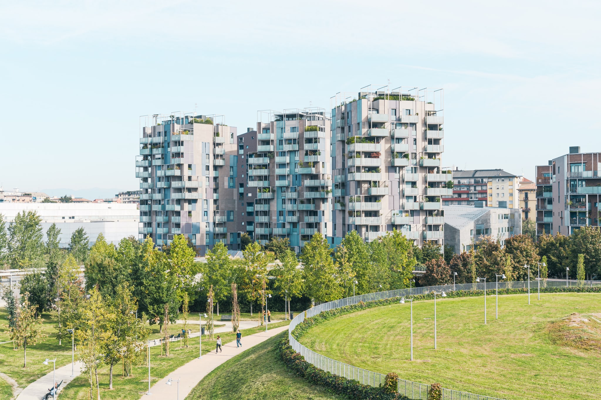 Complesso residenziale contemporaneo con balconi e terrazze, visto oltre un parco alberato