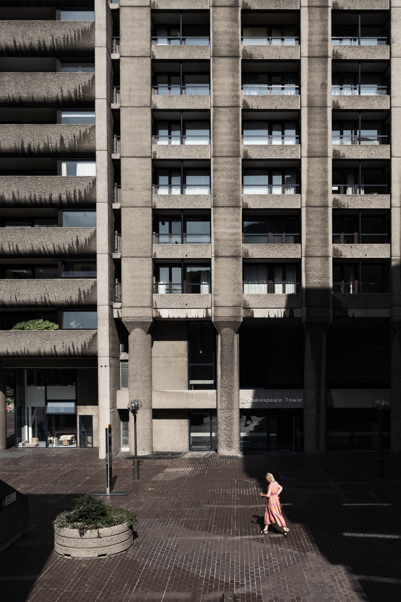 Shakespeare Tower al Barbican di Londra con una donna in abito rosa nella piazza