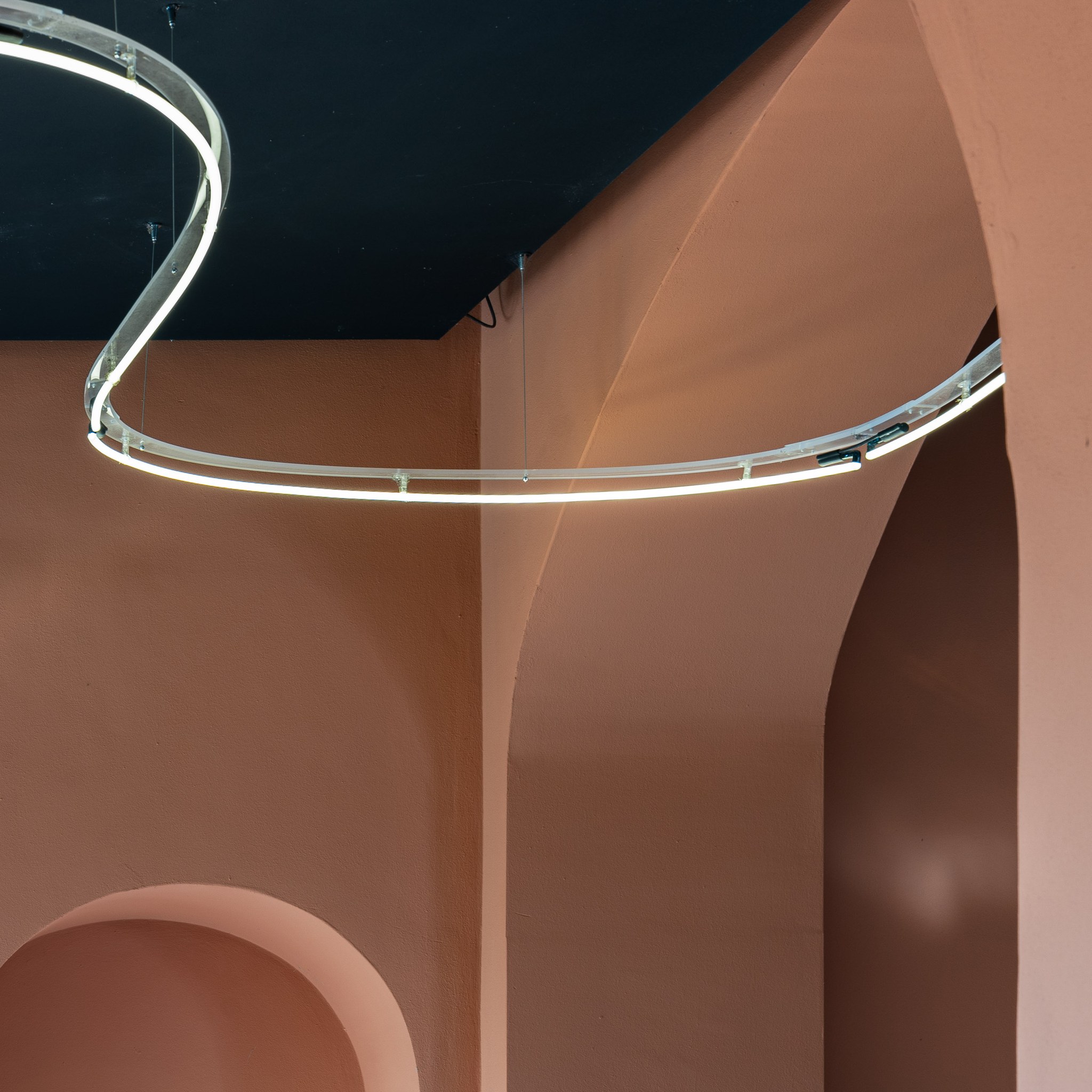 Interno contemporaneo con pareti color terracotta e illuminazione lineare