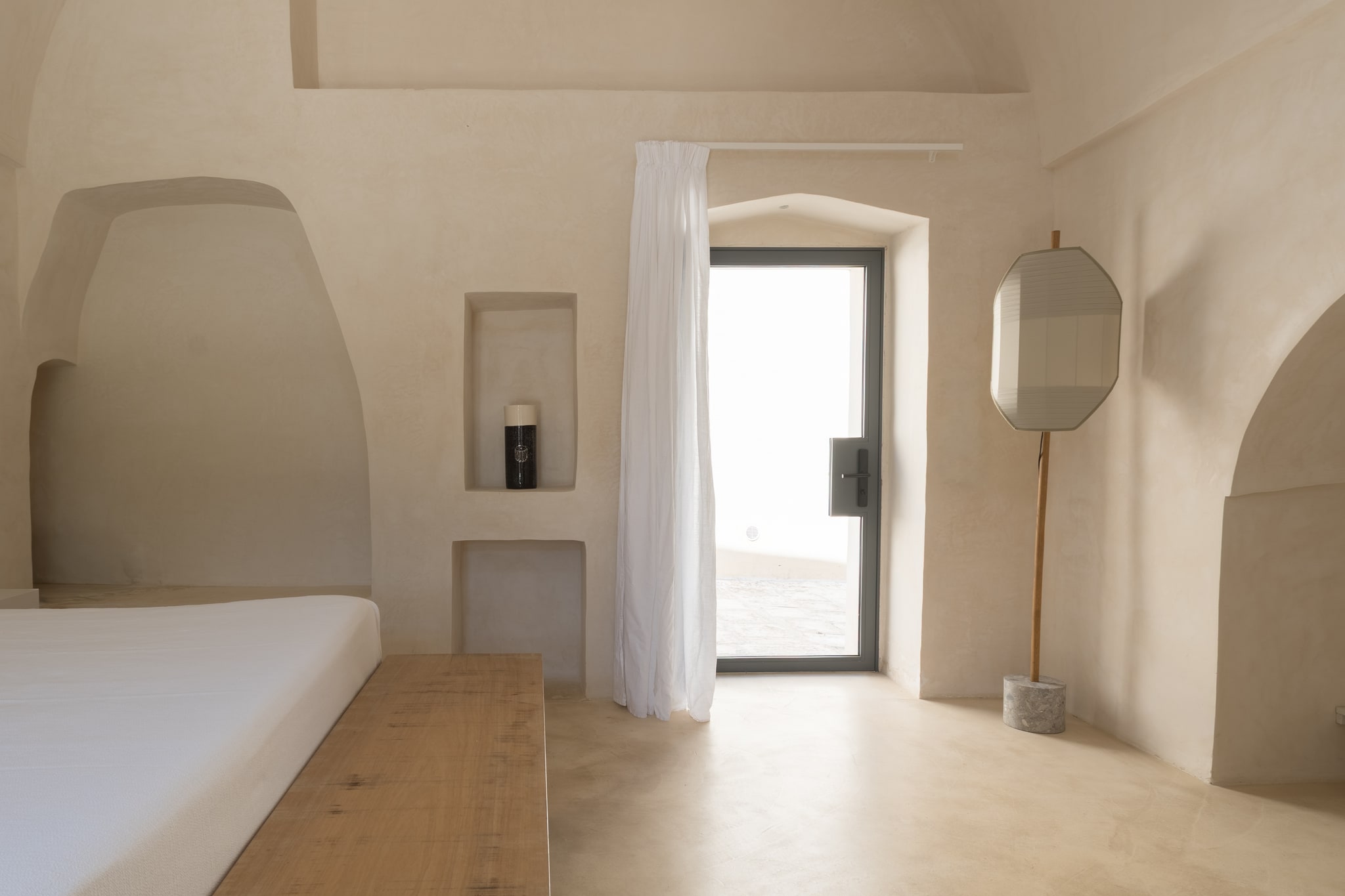 Camera dai toni chiari con porta vetrata, specchio, nicchie e arredi in legno