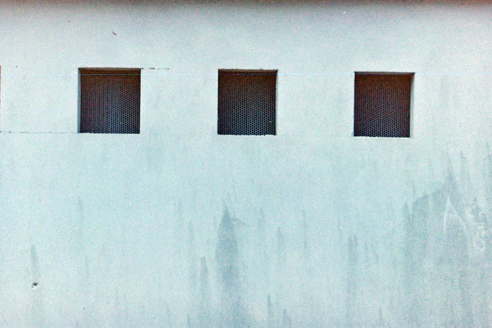 Tre aperture quadrate su una facciata chiara